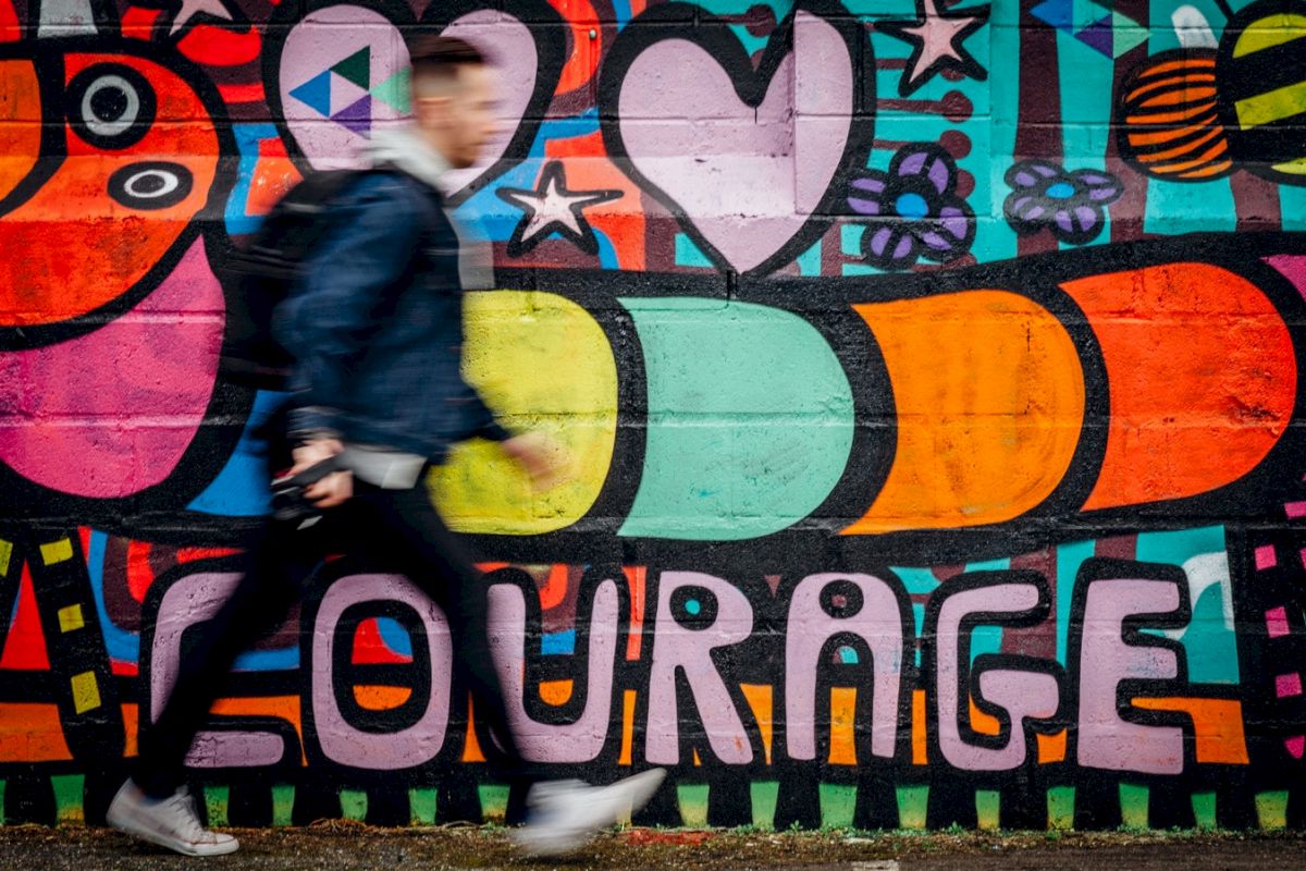 a colorful graffiti mural on a wall with a person walking by