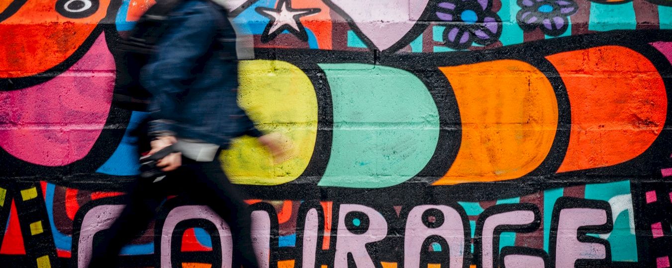 a colorful mural on a wall with a person walking by