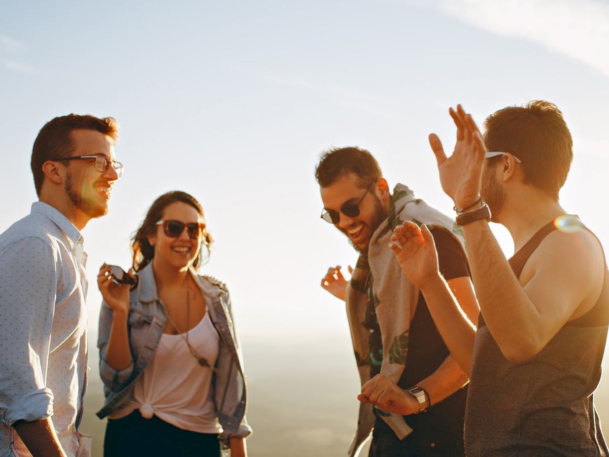 Four people enjoying a sunny day outdoors, smiling and laughing together. They radiate happiness and camaraderie.