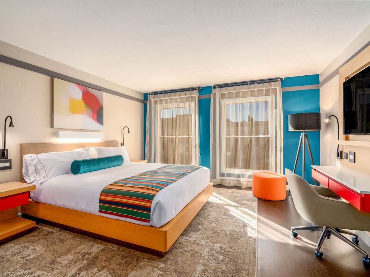 A hotel room with a large bed, desk, and TV