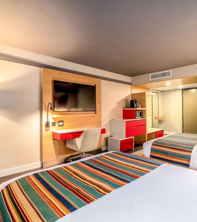 A hotel room with two beds, a desk, TV, microwave, and coffee maker.