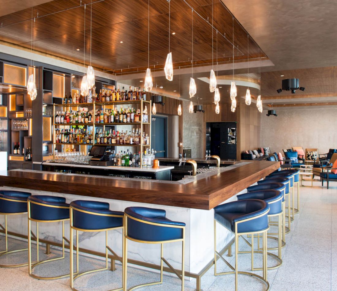 a bar with stools and bottles of alcohol