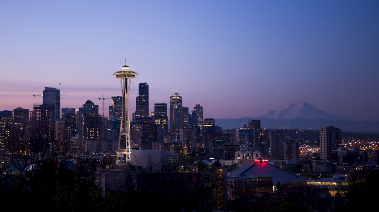 This image features the Seattle skyline at dusk, showcasing iconic landmarks like the Space Needle, with Mount Rainier visible in the background.